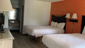 Une chambre d’hôtel avec deux lits, un bureau et un miroir.