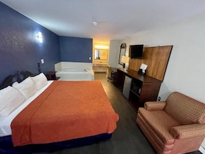 A hotel room with a bed, a sofa, a desk, and a television.
