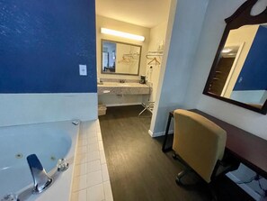 A bathroom with a bathtub, a sink, a mirror, and a chair.