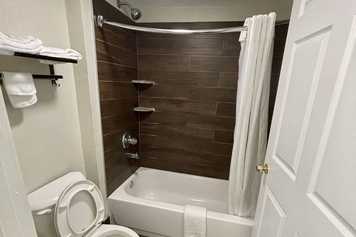 A bathroom with a white toilet, a bathtub with a shower curtain, and a towel rack.