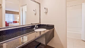 A modern bathroom with a black marble sink, a large mirror, and two wall-mounted hair dryers.