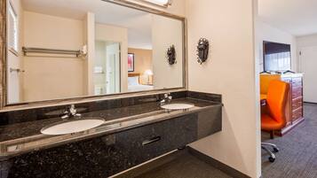 Un baño de hotel con dos lavamanos, un espejo grande y un mueble de tocador con almacenamiento.