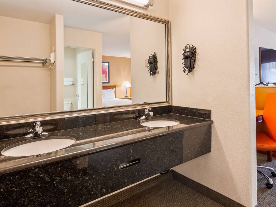 Un baño de hotel con dos lavamanos, un espejo grande y un mueble de tocador con almacenamiento.