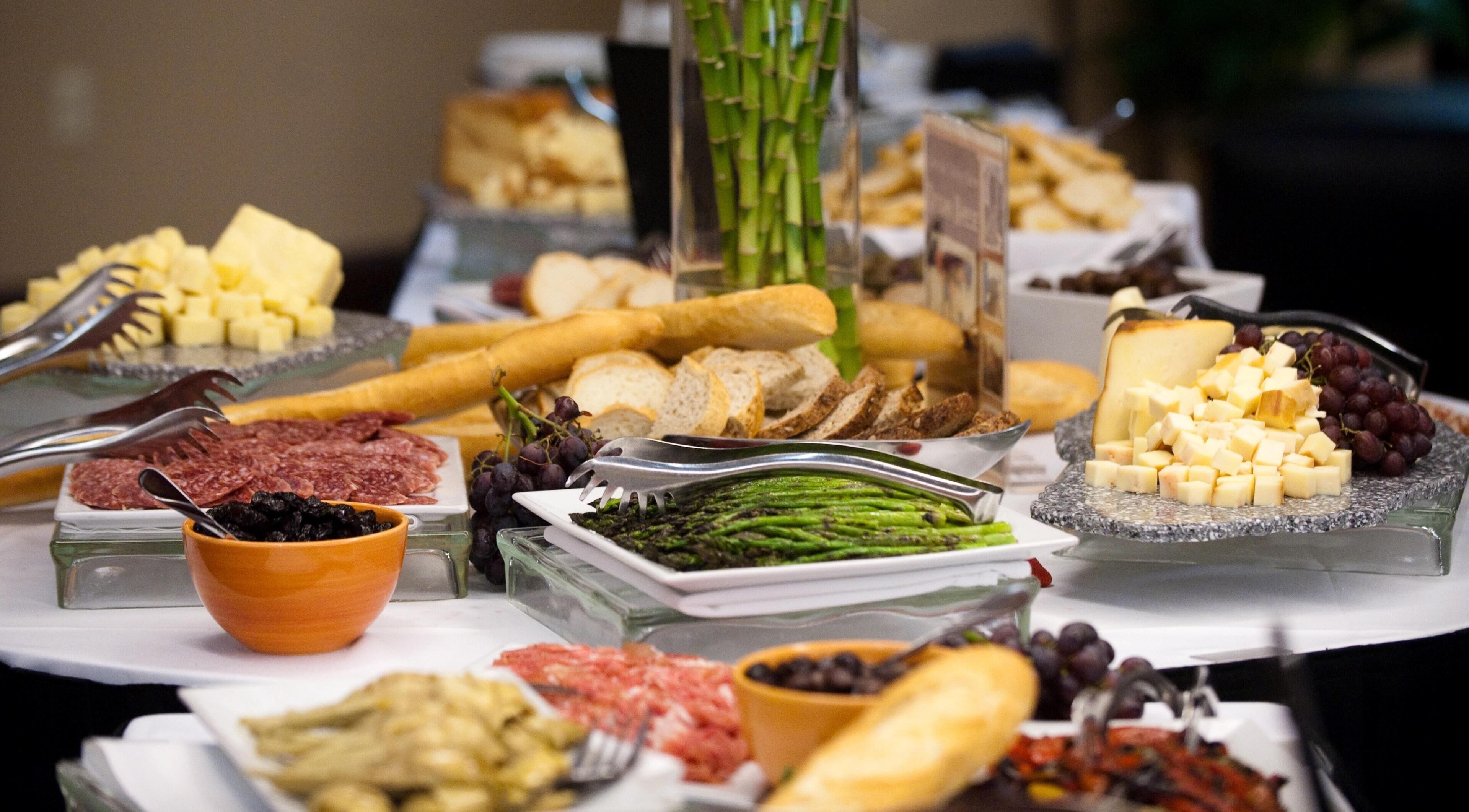 A buffet with various food items including meats, cheeses, fruits, and vegetables.