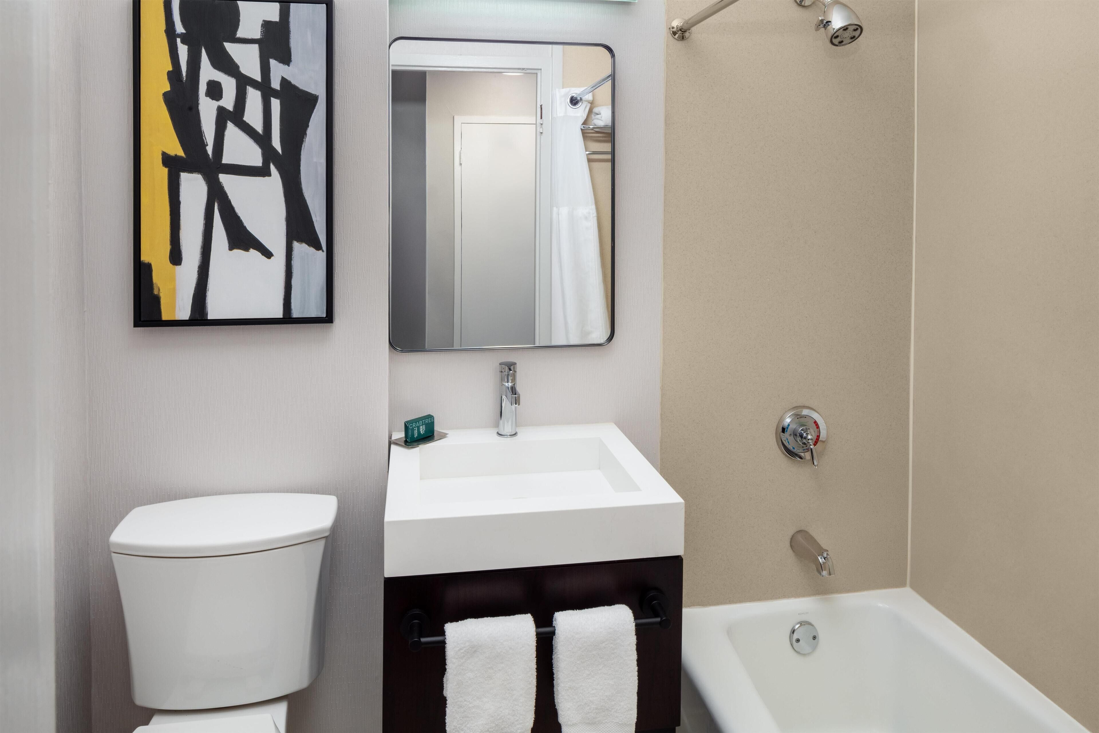 A modern bathroom with a toilet, sink, and bathtub.