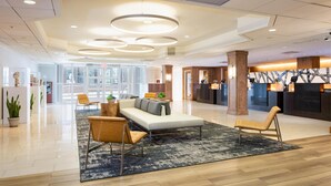 A modern hotel lobby with a reception desk, seating area with sofas and chairs, and a large window providing natural light. - DoubleTree by Hilton Hotel & Suites Pittsburgh Downtown (Pittsburgh)