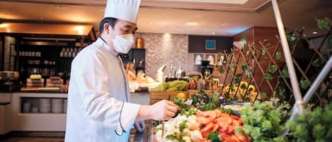 A buffet setup with various food items and a chef in uniform.