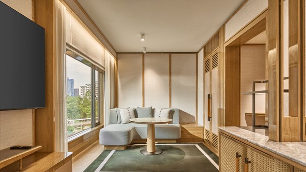 A modern hotel room with a sofa, a round table, and a TV. - Holiday Inn Singapore Orchard City Centre by IHG (Singapore)