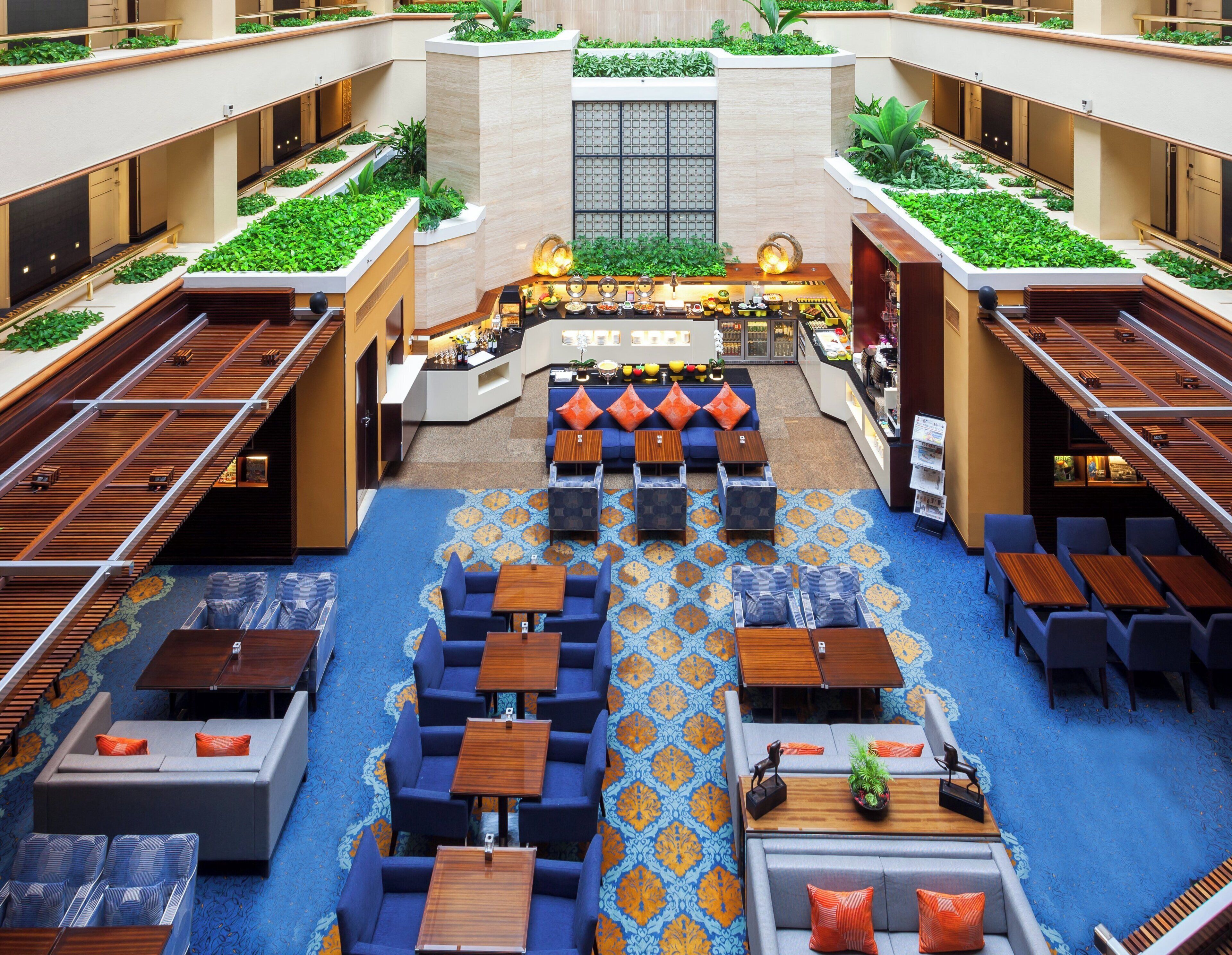 A hotel lobby with a central bar, seating areas, and a patterned floor.