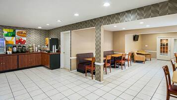 A spacious dining area with a buffet setup, including a refrigerator and various food items.