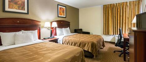 A hotel room with two beds, a desk, a chair, and a large window with curtains.