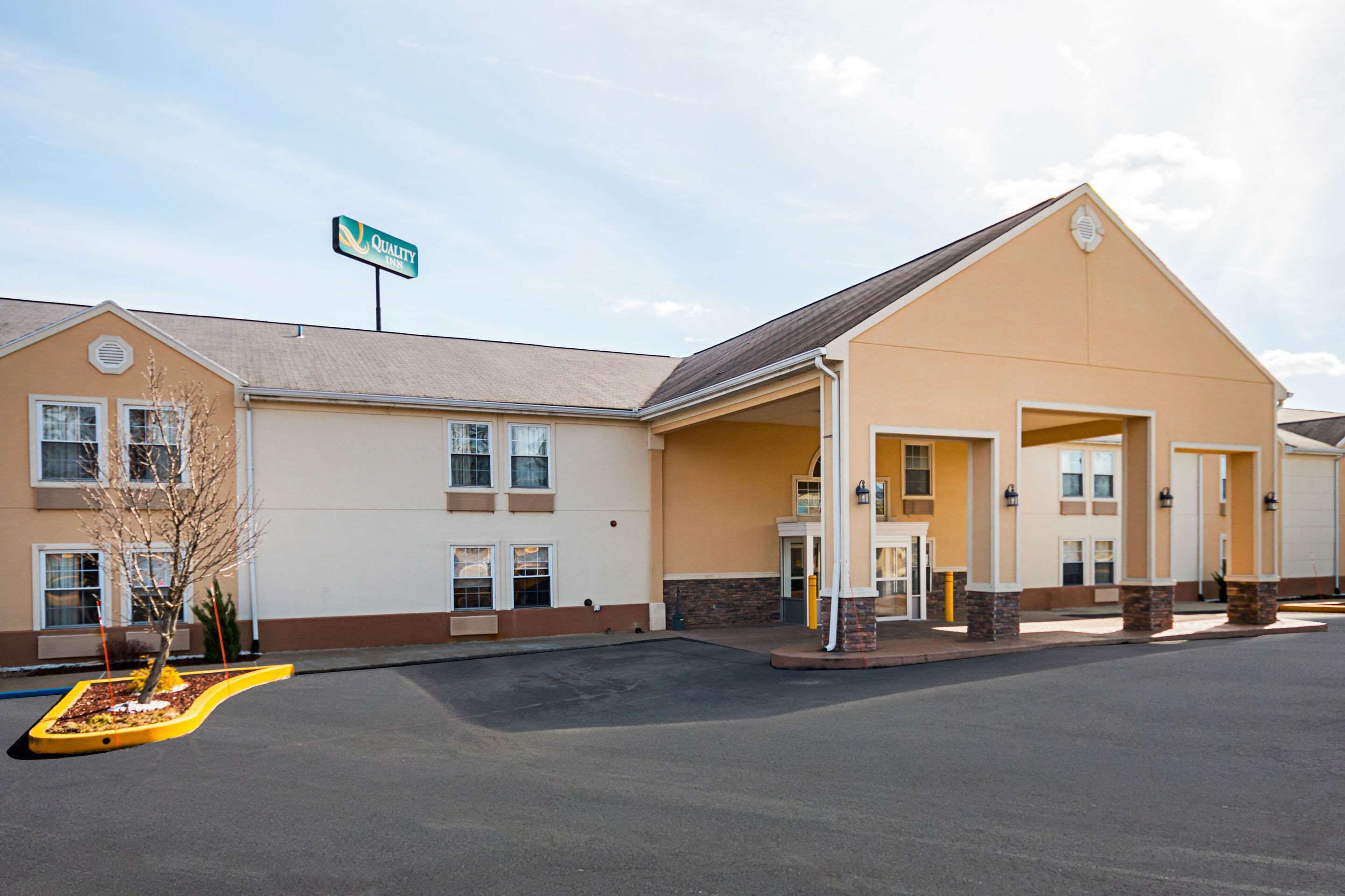 A hotel with a large entrance, a sign indicating 'Quality', and a parking lot.