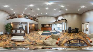 A spacious lobby with a high ceiling, a central seating area, and a reception desk.