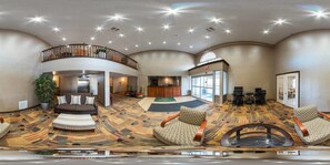 A spacious lobby with a high ceiling, a central seating area, and a reception desk.