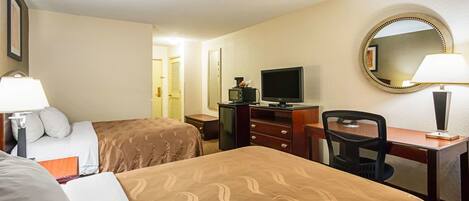 A hotel room with two beds, a desk with a chair, a television, and a mirror.