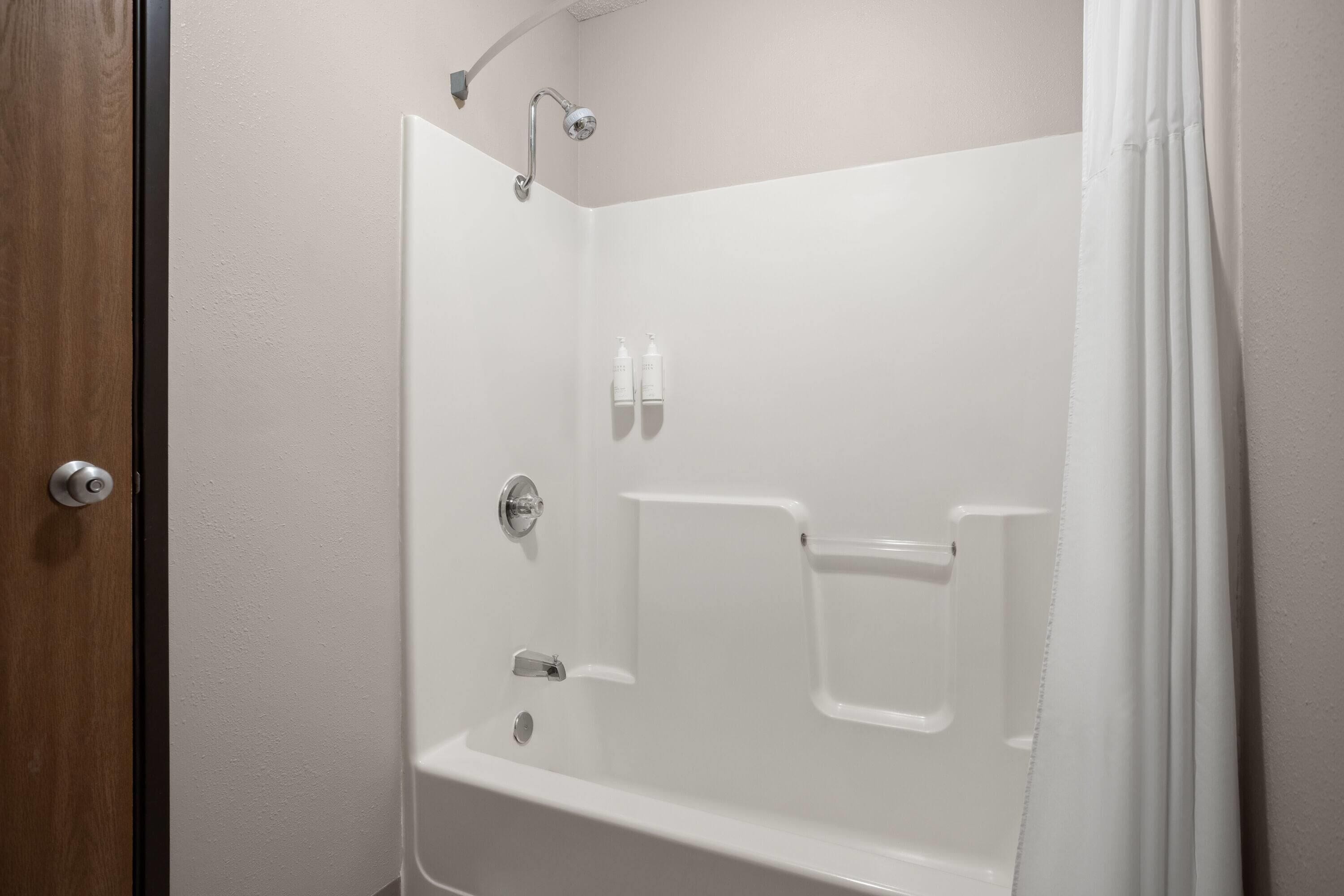 Un baño blanco con tres duchas de mano.