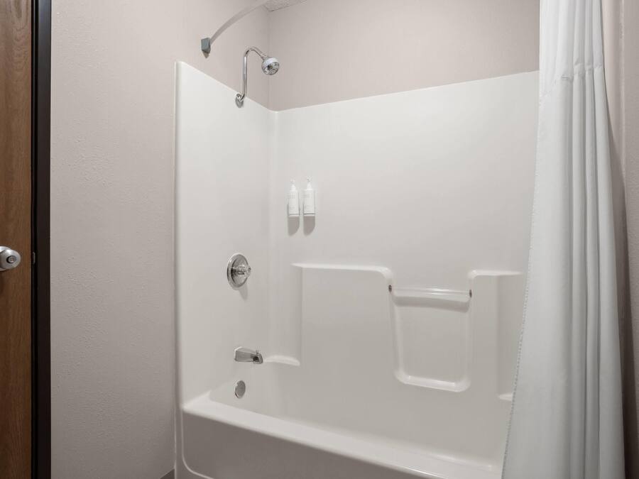Un baño blanco con tres duchas de mano.