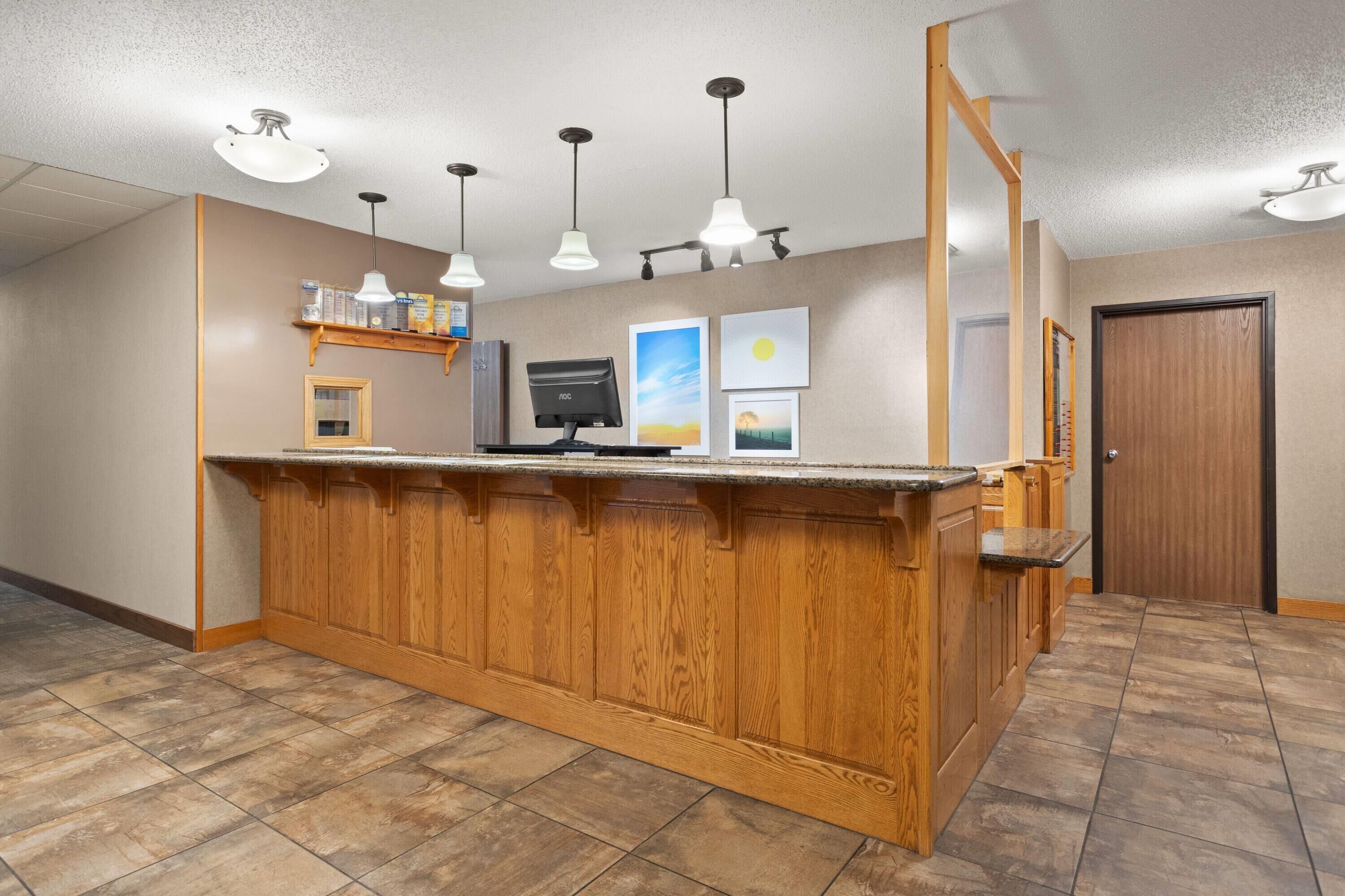 A reception area with a wooden counter, pendant lighting, a computer monitor, and framed artwork on the wall.