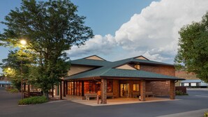 A hotel with a brick exterior, large windows, and a covered outdoor area with benches. - Days Inn by Wyndham Spearfish (Spearfish)