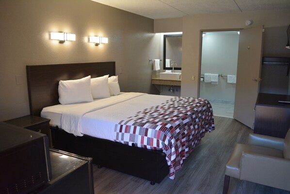 Cozy retreat with a neatly made bed, bedside table, and desk for a comfortable stay.