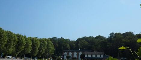 A lakeside view with a building, trees, and a clear sky.
