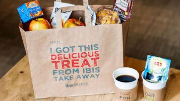 Una bolsa de papel con un mensaje, una taza de café y un recipiente de té Lipton.