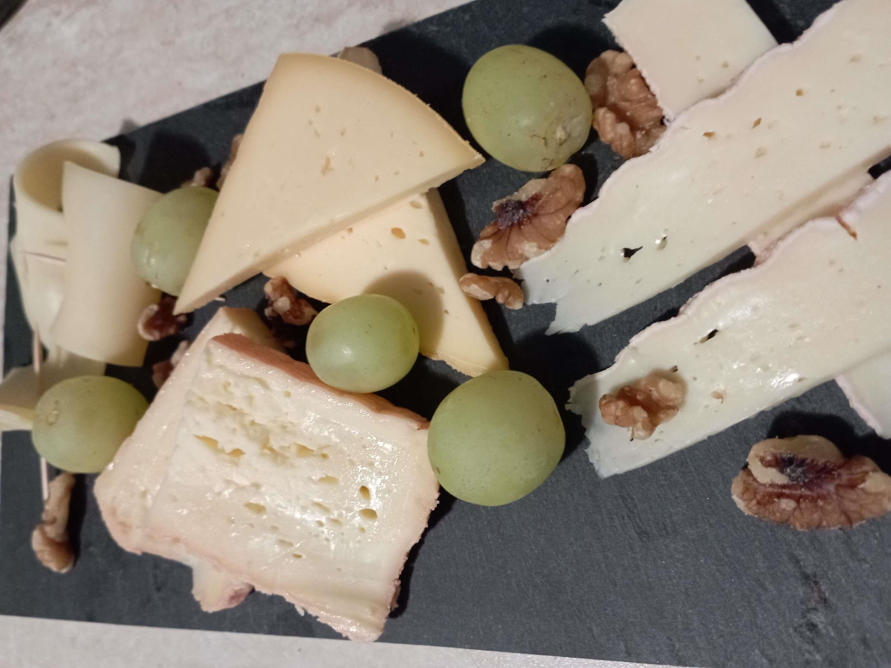 Una tabla de quesos con diferentes tipos de queso, uvas y nueces.