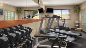 Un gimnasio con cintas de correr, mancuernas y equipo de ejercicio.