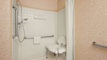 Un baño con ducha, barras de apoyo, un inodoro blanco y una bañera blanca.