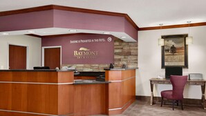 Un mostrador de recepción con un cartel que indica "Está prohibido fumar en este hotel" y la marca "Baymont Inn & Suites".