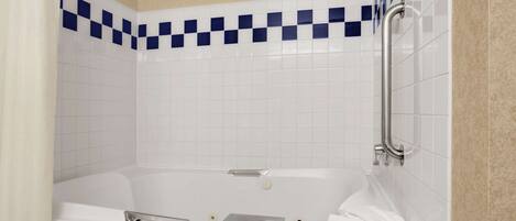 Un baño moderno con una bañera blanca, un cabezal de ducha de mano y una barra de apoyo.