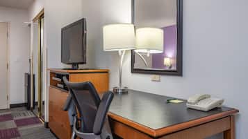Une chambre d’hôtel équipée d’un bureau en bois, d’une télévision, d’une lampe, d’un téléphone et d’un miroir.