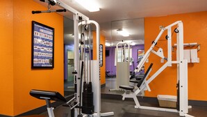 A gym with various exercise machines, a poster on the wall, and a mirror reflecting the equipment. - Atherton Park Inn & Suites (Redwood City)
