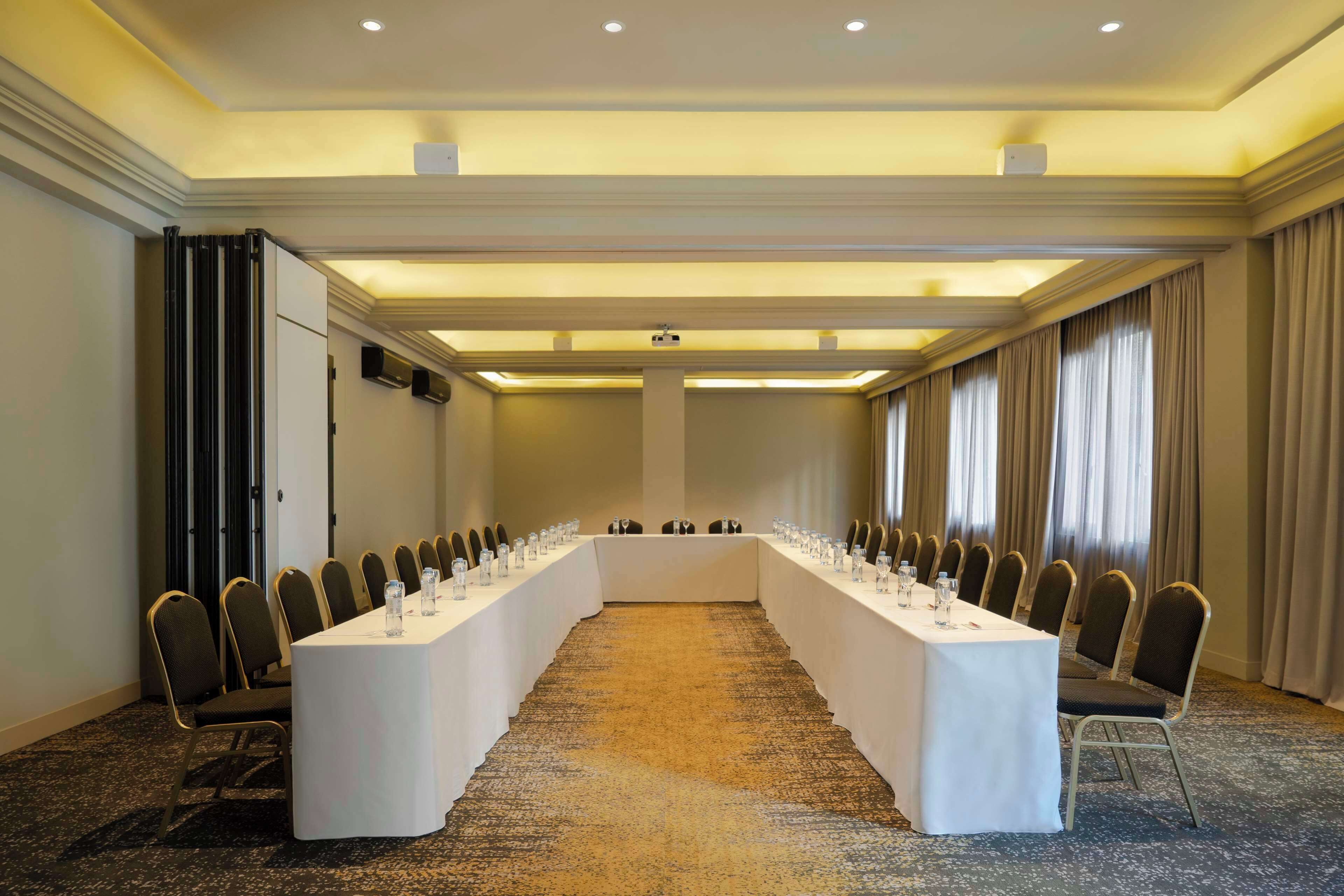 A conference room with a long table, chairs, and a carpeted floor.