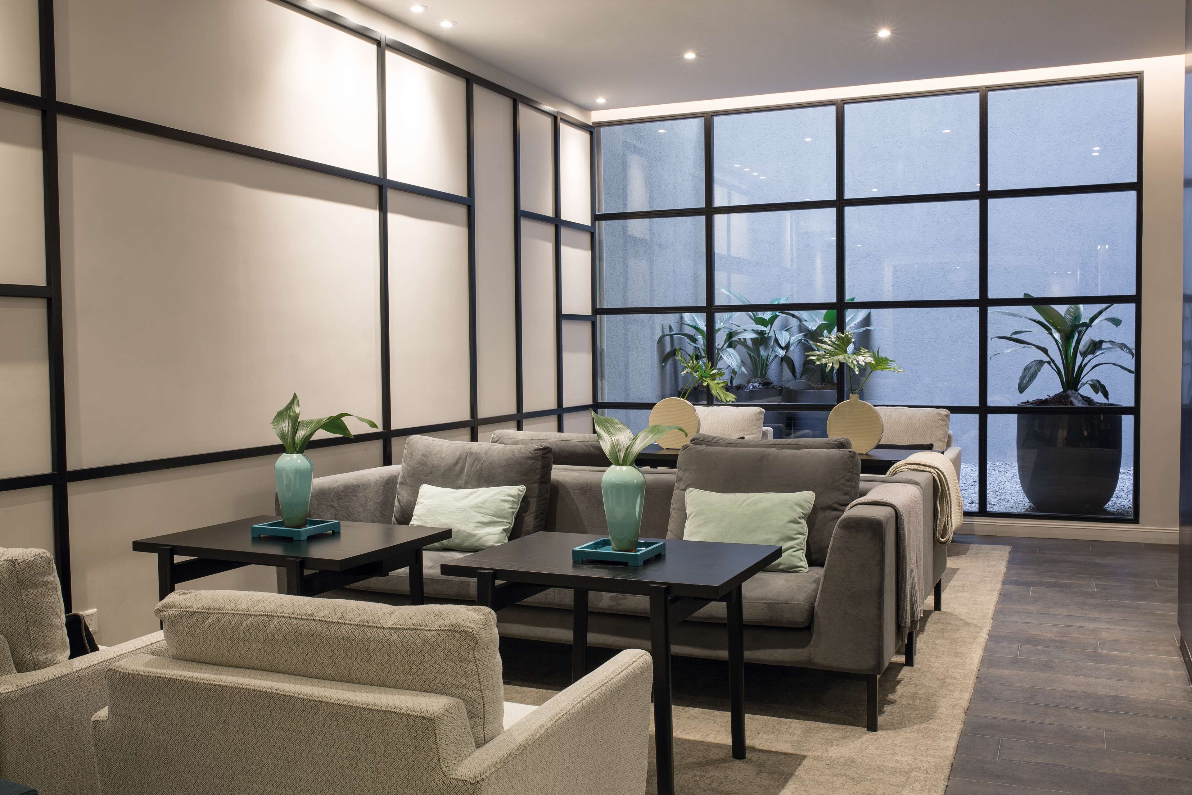 A modern living room with a sofa set, two side tables, and a large window with a view.