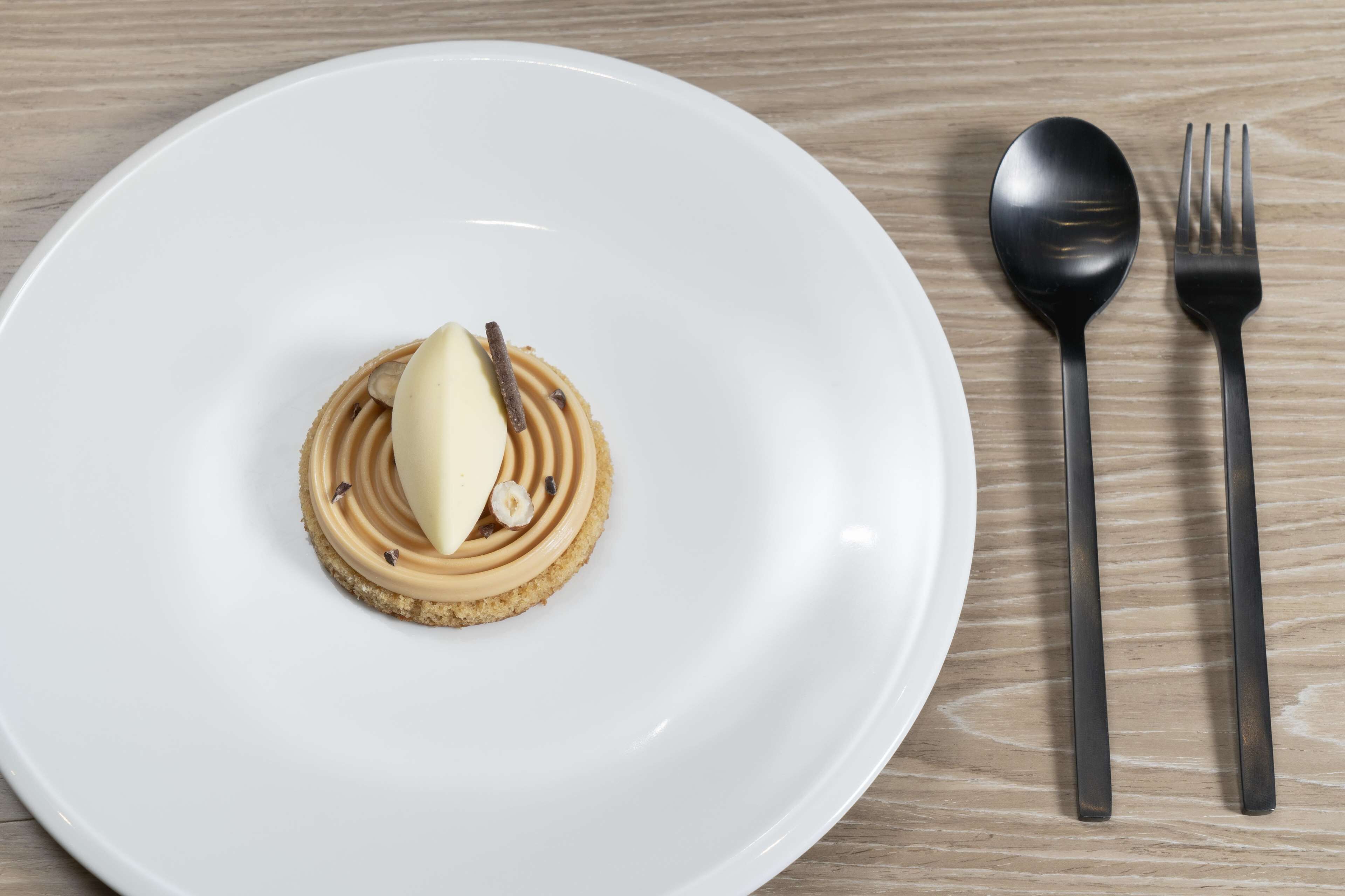 Ein weißer Teller mit Dessert auf einem Holztisch.