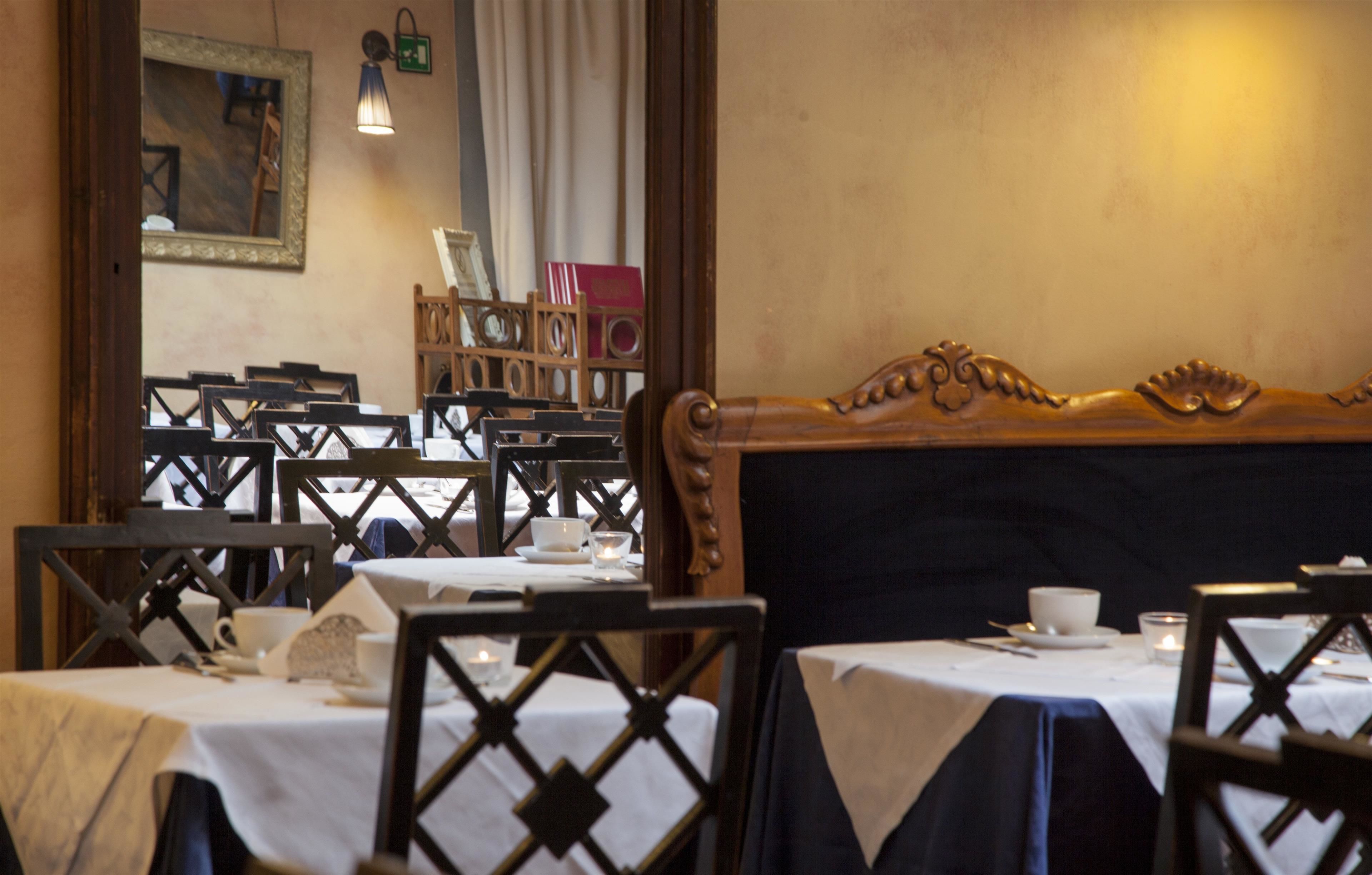 Un restaurant avec plusieurs tables et chaises, un banc en bois et un miroir au mur.