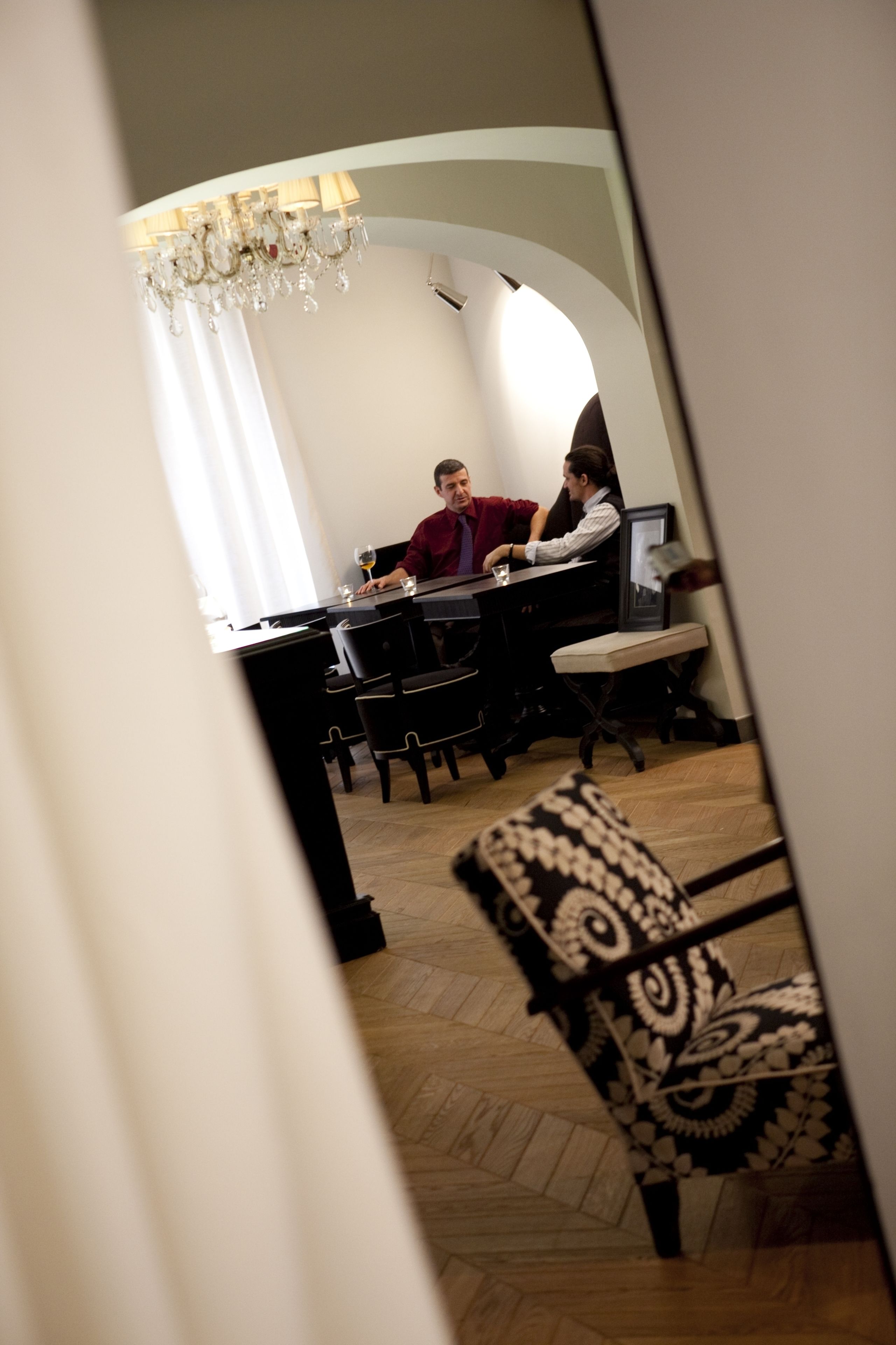Un coin repas agrémenté d’un lustre, d’une table avec des chaises et d’un fauteuil à motifs.