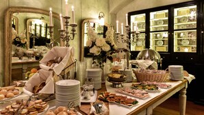 Montaje de bufé con diferentes alimentos, platos y un espejo que refleja la decoración del salón.
