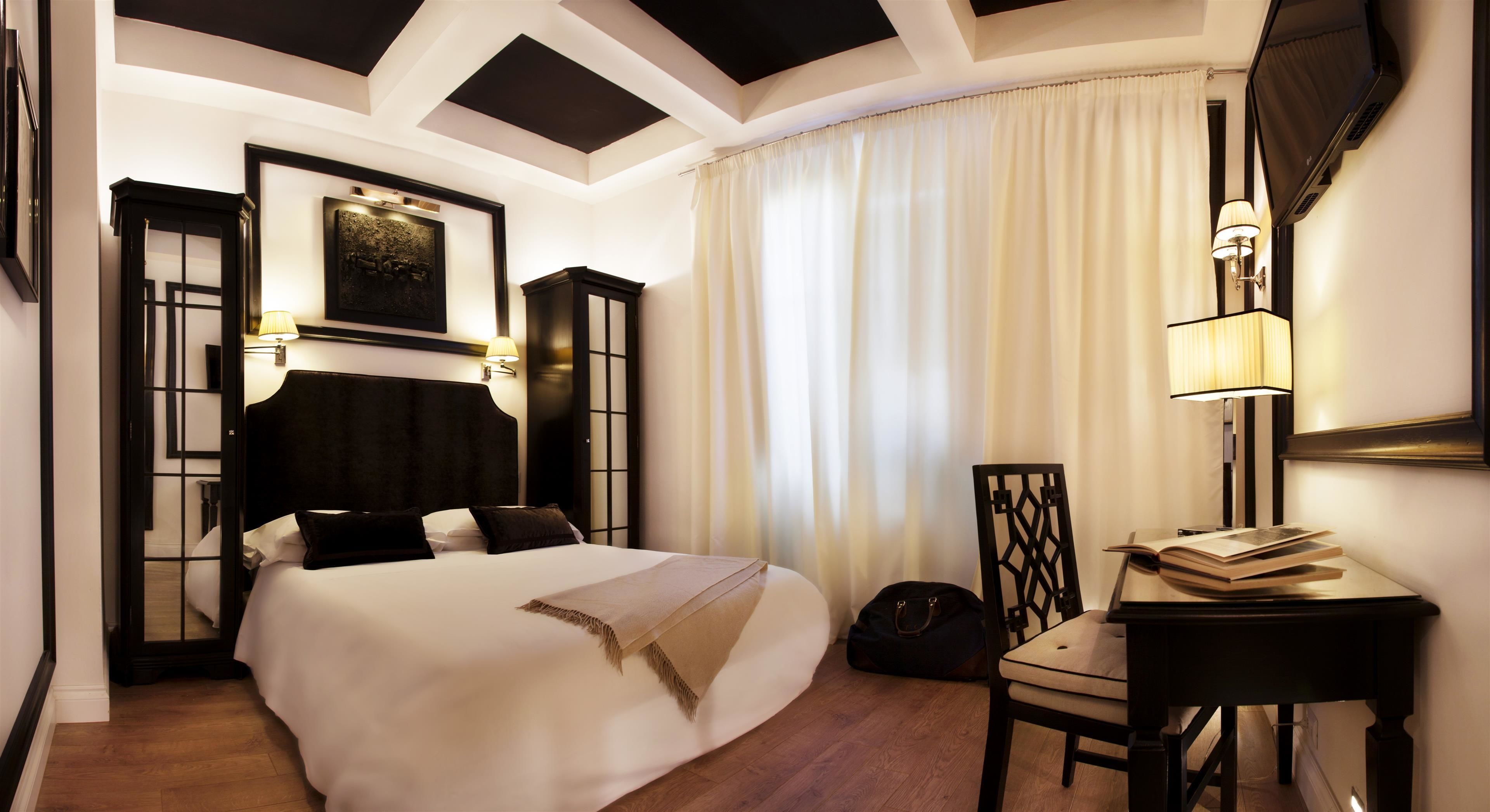 Une chambre d’hôtel avec un grand lit, un bureau avec une chaise, une lampe et un téléviseur fixé au mur.