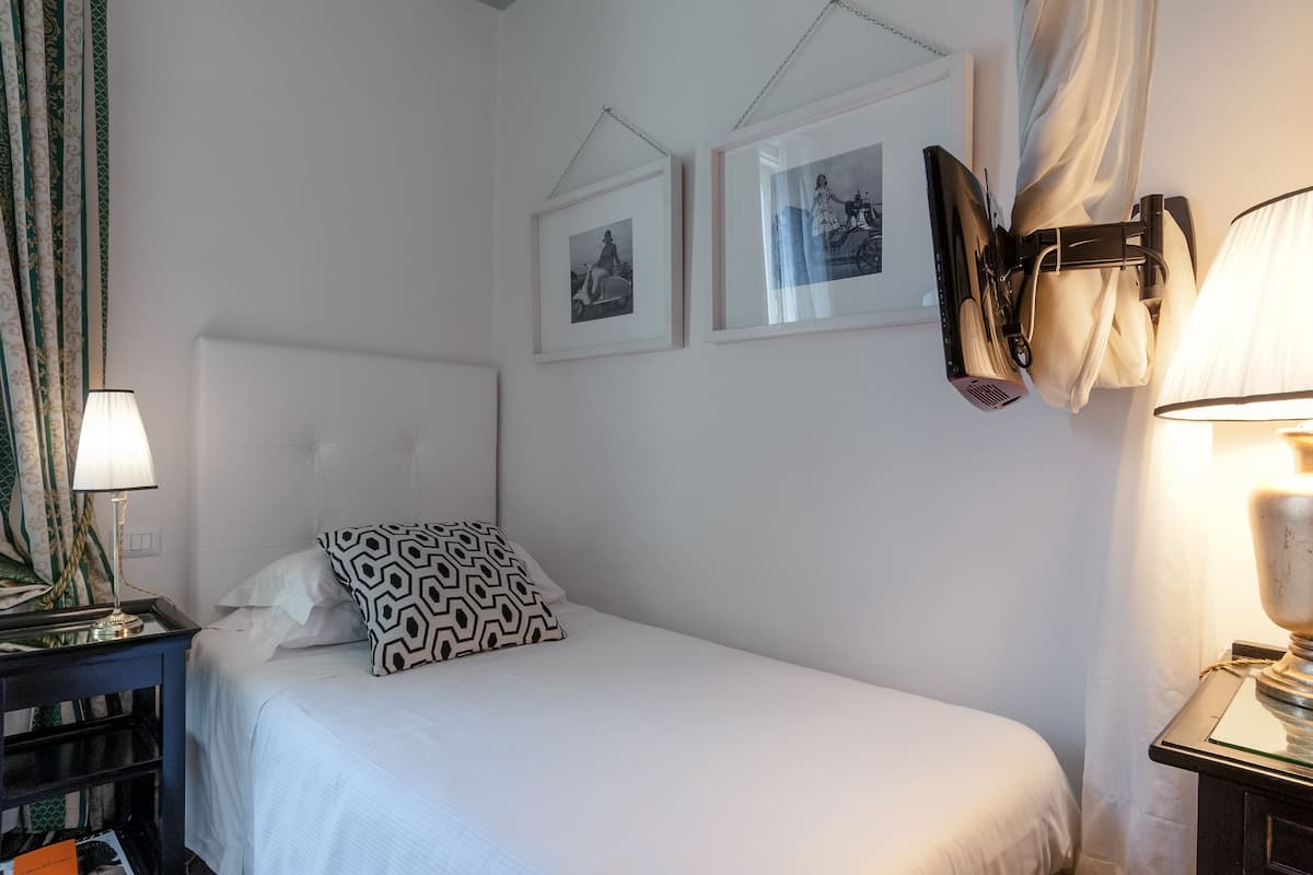 A neatly made bed with a patterned pillow, a bedside lamp, and two framed pictures on the wall.