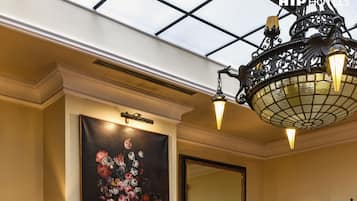 Experience the epitome of elegance in this inviting hotel room, featuring a stunning chandelier, plush seating, and a warm fireplace.