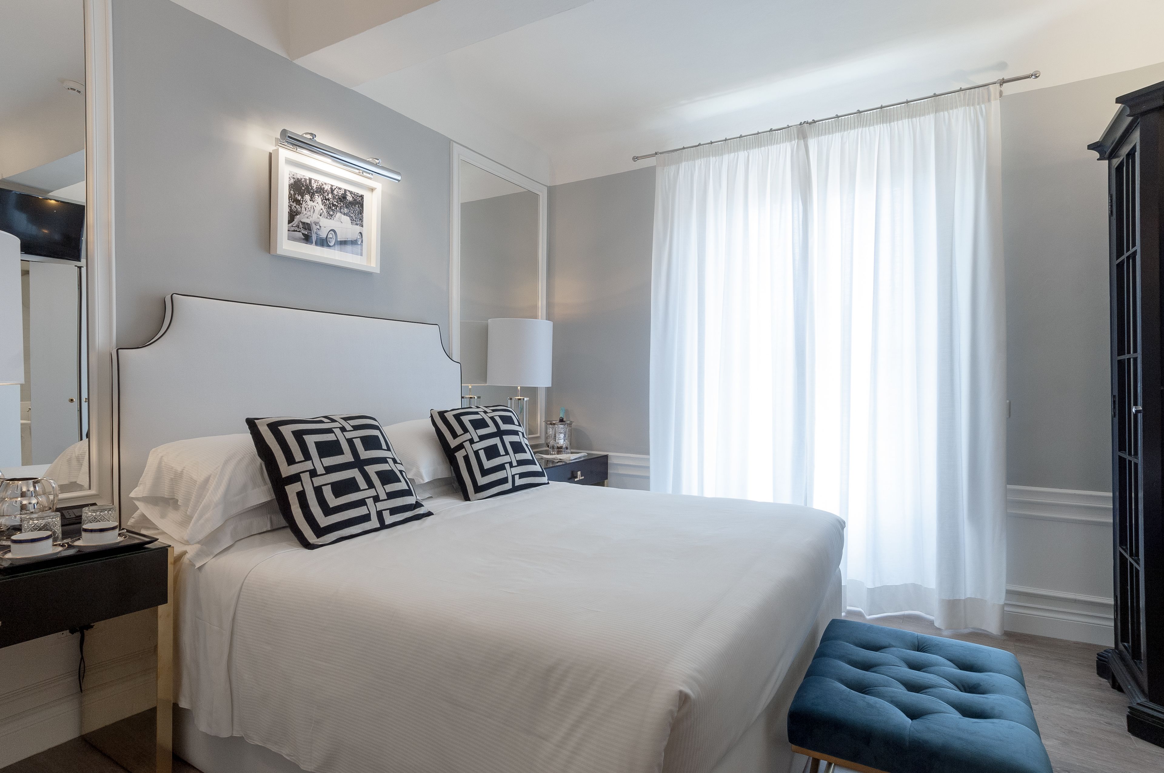 Una camera da letto ordinata con un letto grande, un comodino con una lampada, uno specchio e un quadro appeso al muro.