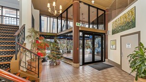 A spacious lobby with a staircase, a Christmas tree, and a large window. - Bedford Regency Hotel, Trademark Collection by Wyndham (Victoria)