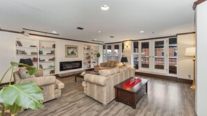 A living room with a fireplace, bookshelves, a sofa, and a coffee table. - Bedford Regency Hotel, Trademark Collection by Wyndham (Victoria)