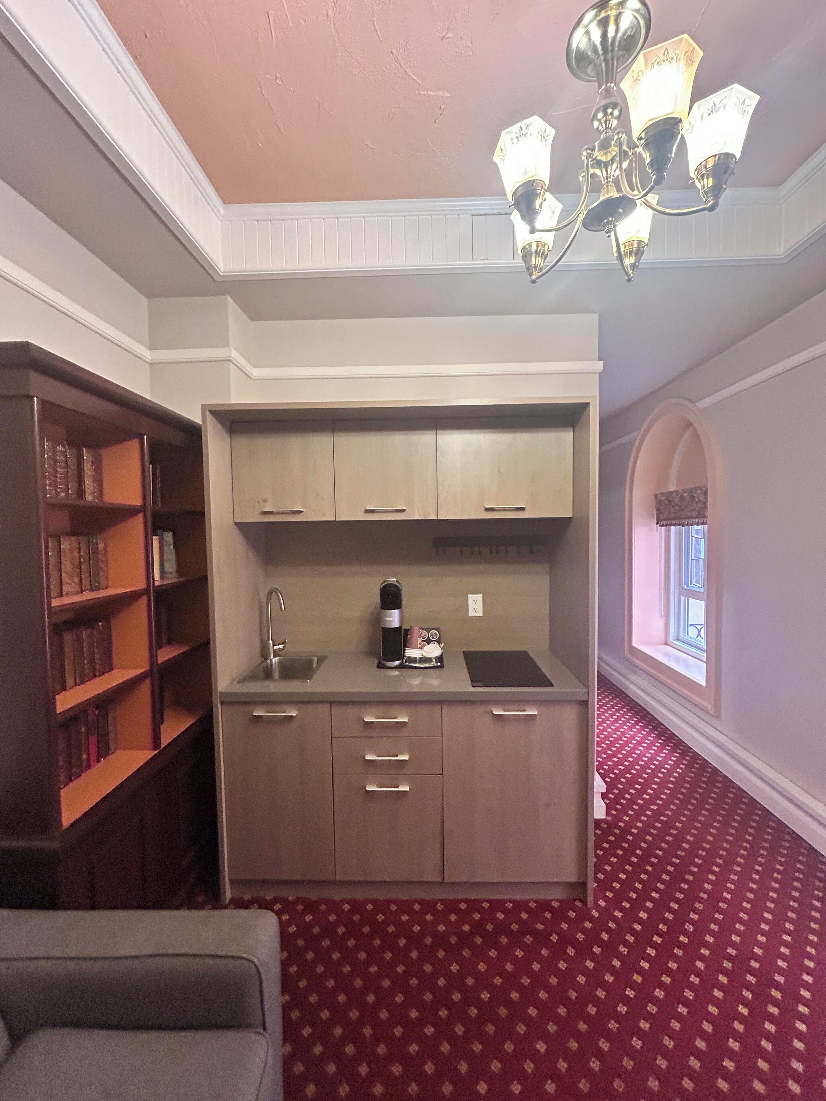A compact kitchen with built-in cabinets, a coffee maker, and a window.