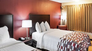 A hotel room with two beds, a nightstand with a lamp, and a window with curtains. - Red Roof Inn Indianapolis East (Indianapolis)