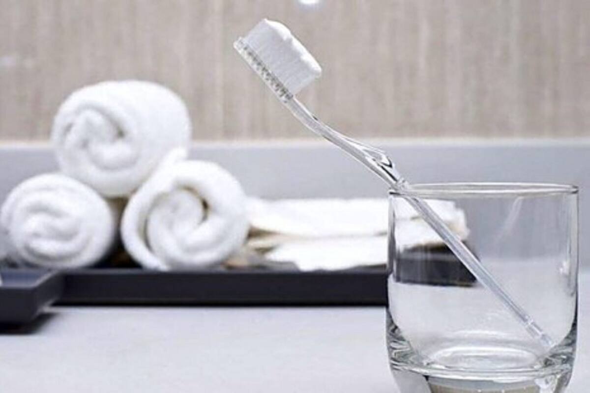 Un vaso de agua con un cepillo de dientes y una pastilla de jabón en una bandeja.