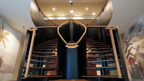 A modern interior with a central staircase, a circular wooden platform, and a ceiling with recessed lighting. - Mercure Perpignan Centre (Perpignan)