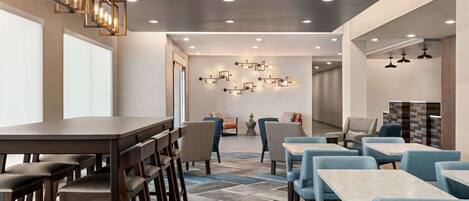 Un interior de restaurante moderno con una larga mesa común, varios reservados y un suelo estampado.